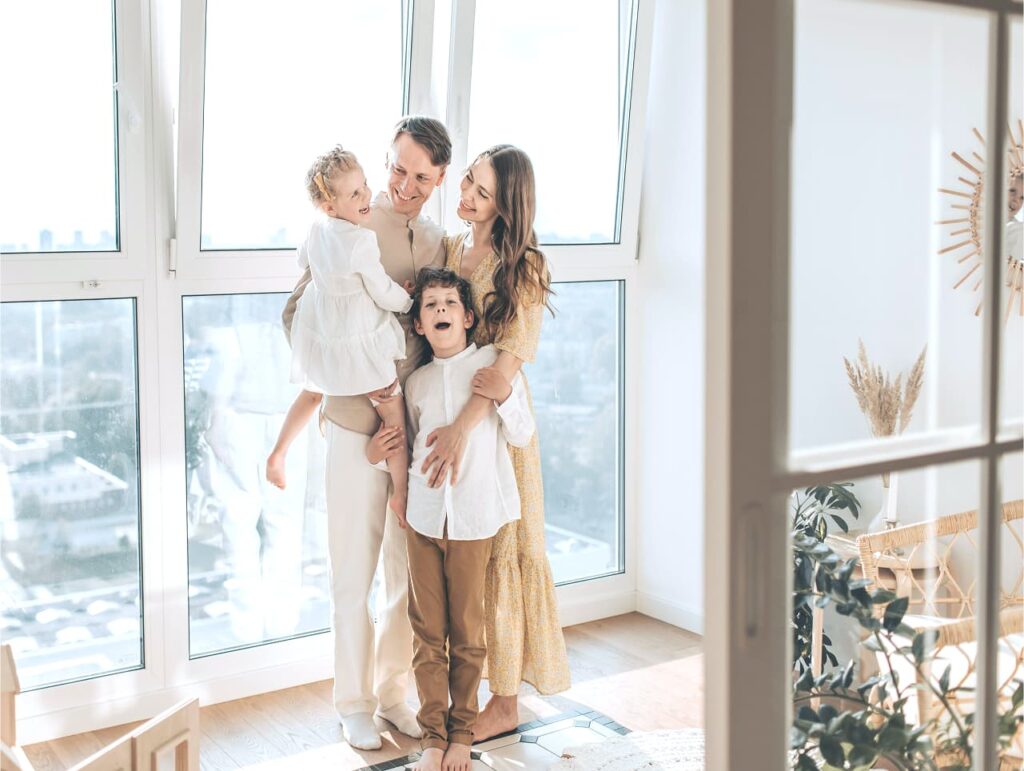 Rodzina w jasnym wnętrzu przy oknach.