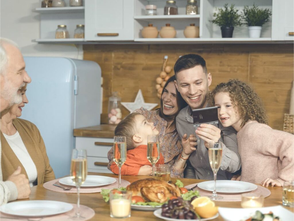 Rodzinna kolacja, wszyscy uśmiechnięci przy stole.