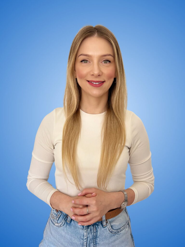 Paulina Stępniewska w jasnej bluzce na niebieskim tle. Paulina jest przyjazną i kompetentną ekspertką kredytową wspierającą swoich klientów.