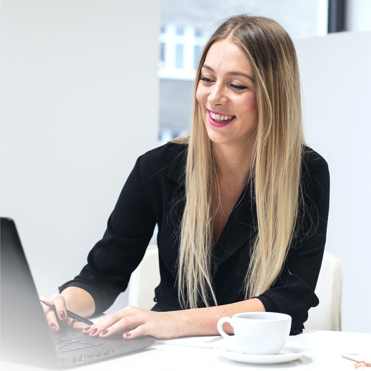 Kobieta pracująca przy laptopie z kawą.